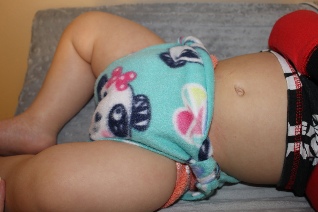 Bottom half of a baby wearing a teal panda print fleece diaper.