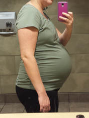 Profile of pregnant belly. Picture taken in a mirror, background of public restroom.
