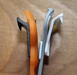 Comparing the teeth on the Boingo and Snappi. Close up of fastener teeth side by side with wood background. Orange Boingo with black teeth is on the right. Grey Snappi with white teeth on the left. The teeth gripper piece is flush on the Boingo and pulls away a bit on the Snappi. There is no visual difference between the teeth themselves besides color.